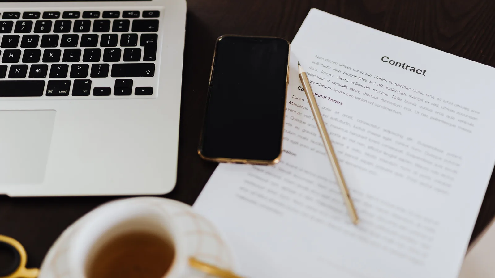 A contract document on a desk beside a laptop, ready for review