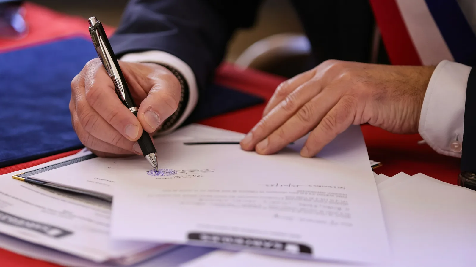 Une main signant un document officiel au stylo